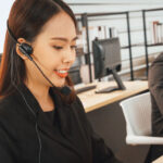 A customer service rep speaks on a headset in an office