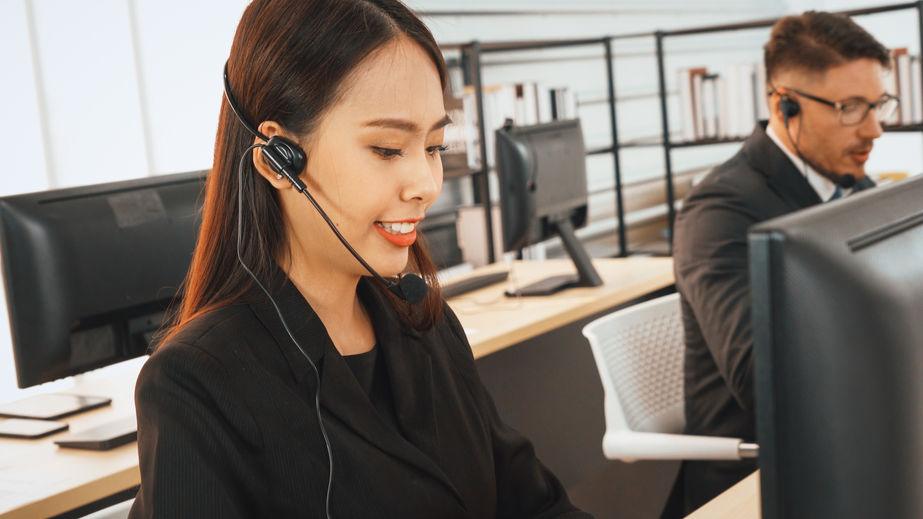 A customer service rep speaks on a headset in an office